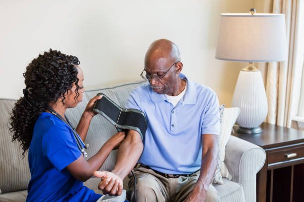 istockphoto-1297322906-612x612 A healthcare worker visiting a senior African-American man in his home, checking his blood pressure. The man is in his 70s and the nurse is a mature woman in her 40s.